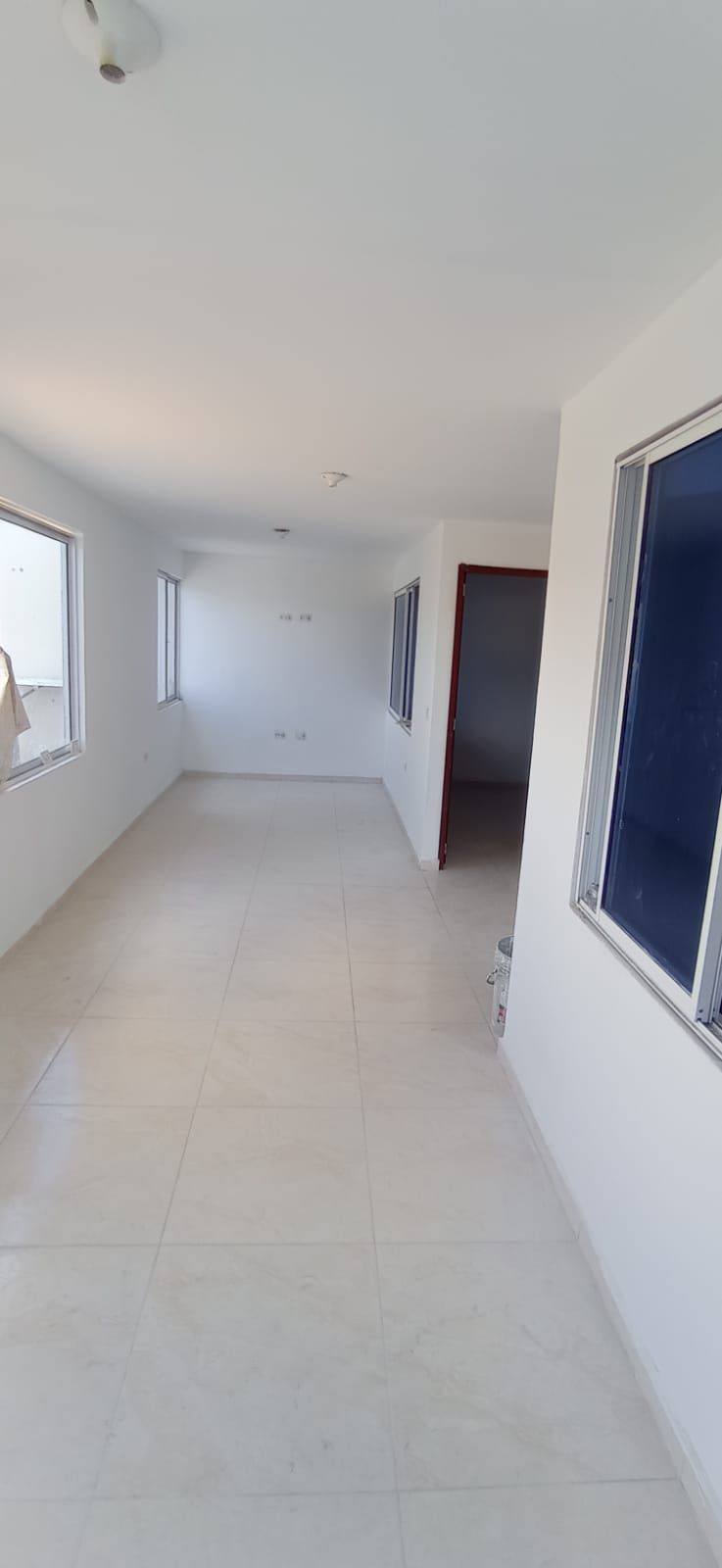 Una gran habitación vacía con muchas ventanas y una puerta.