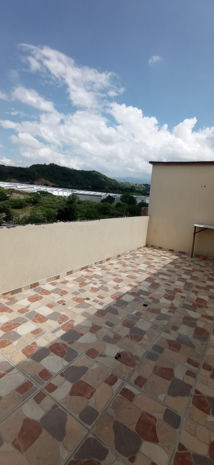 Una terraza en la azotea con vista a un cuerpo de agua y montañas.