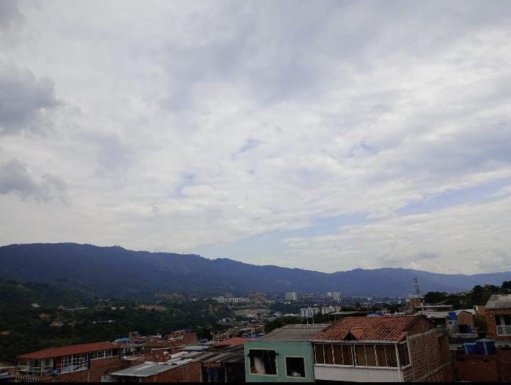 Una ciudad con montañas al fondo y un cielo nublado