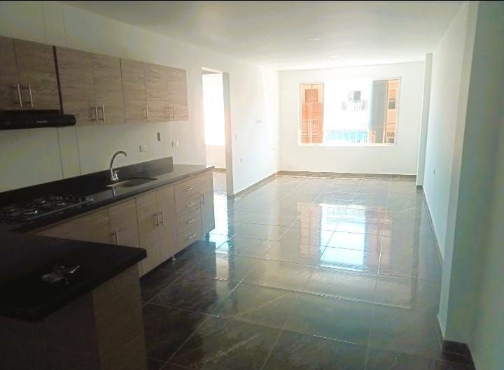 Una cocina con fregadero, estufa y gabinetes en una habitación vacía.