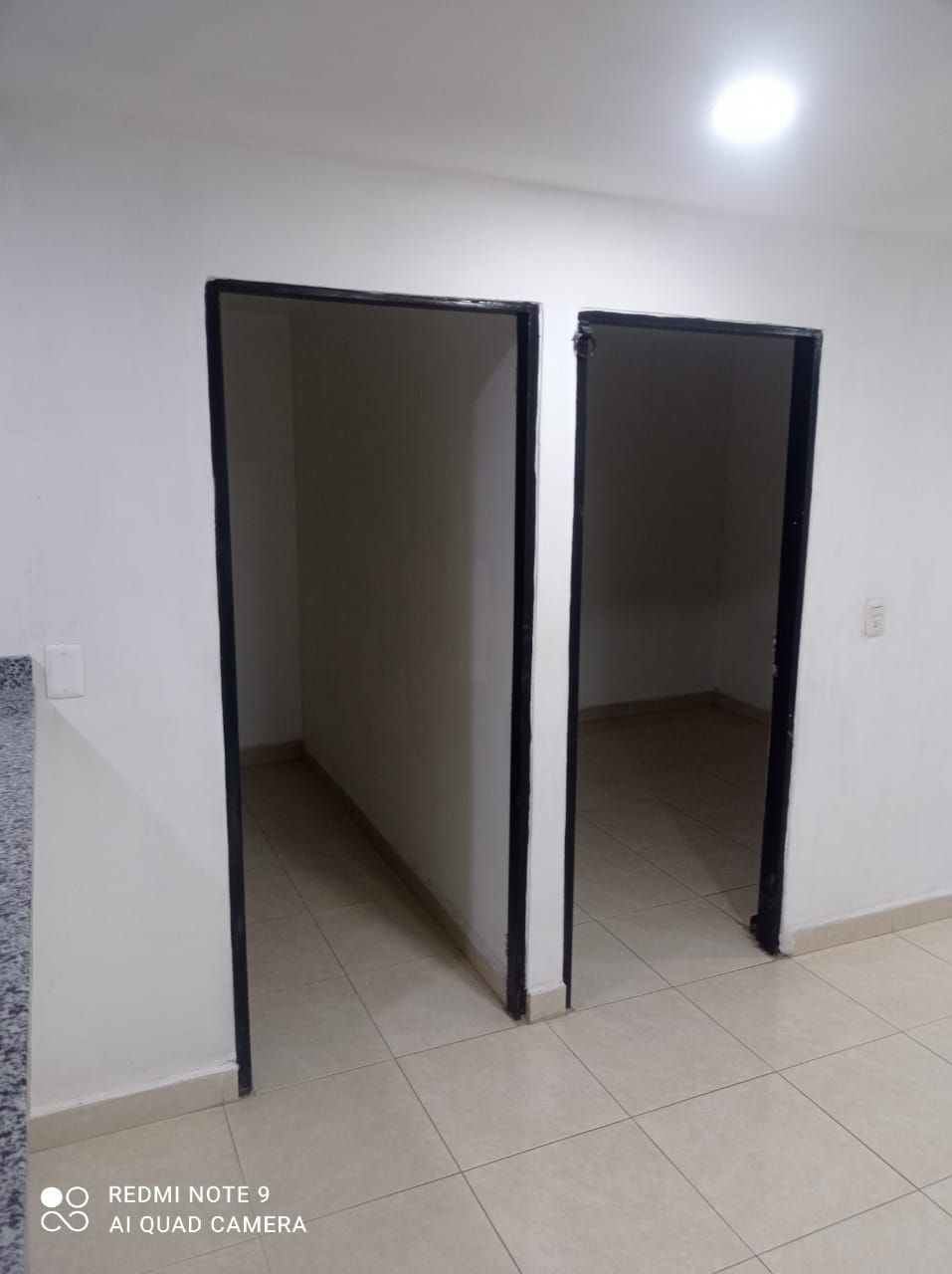 Una habitación vacía con dos puertas abiertas y un Redmi Note 8