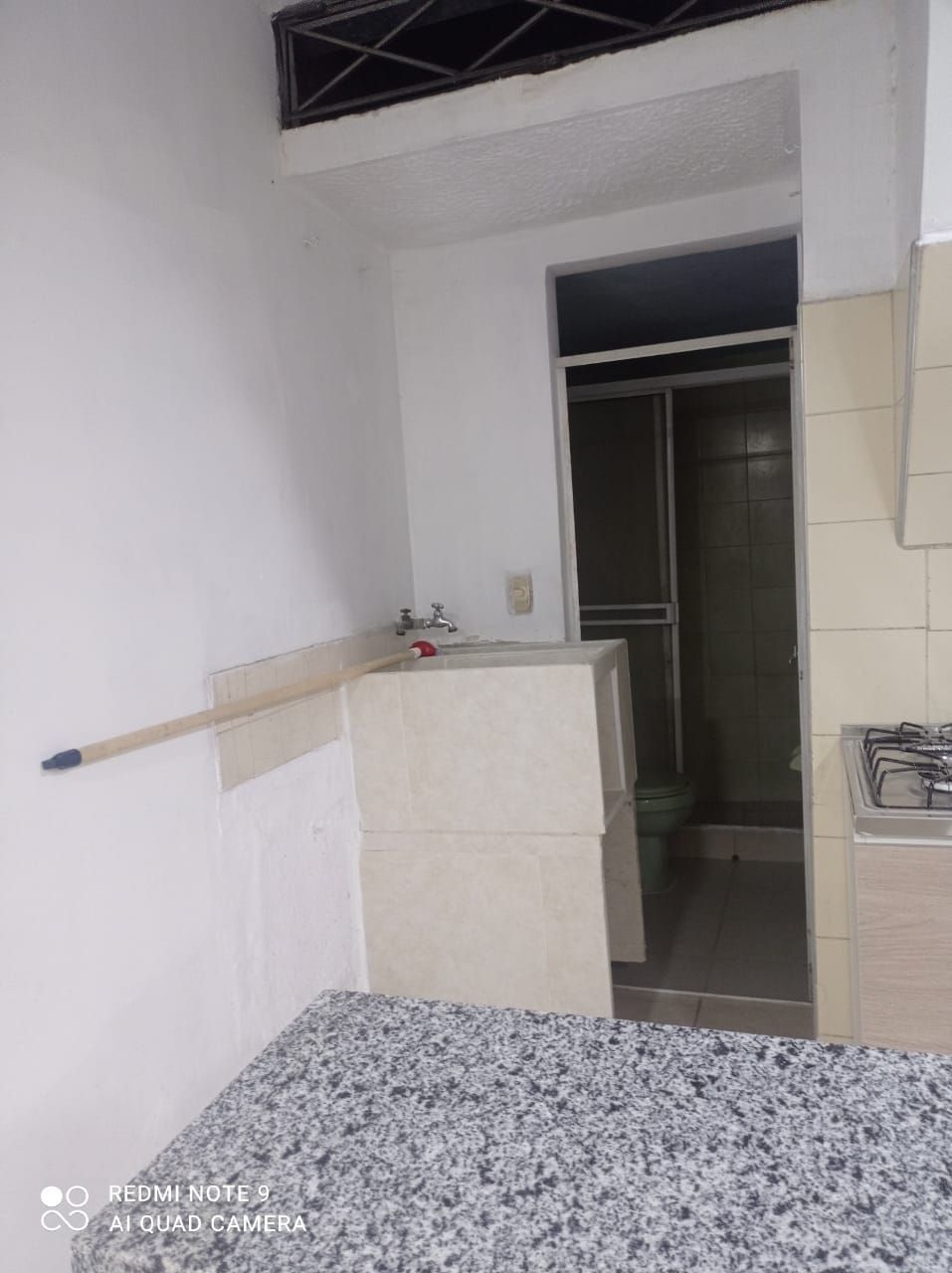 Una cocina con estufa, fregadero y inodoro.