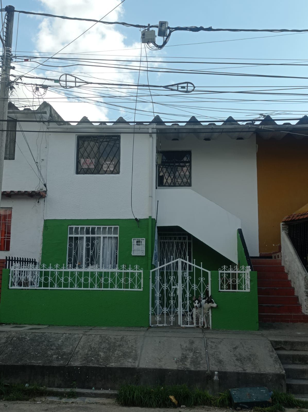 Una casa verde y blanca con escaleras que conducen a ella.