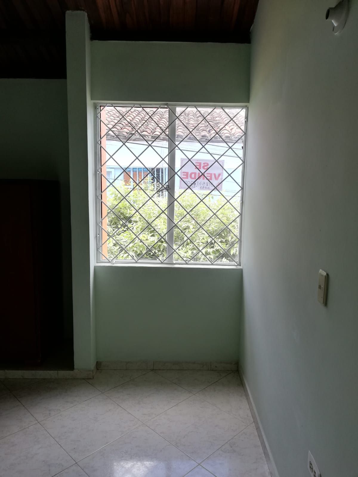 Una habitación vacía con una ventana con una valla alrededor.