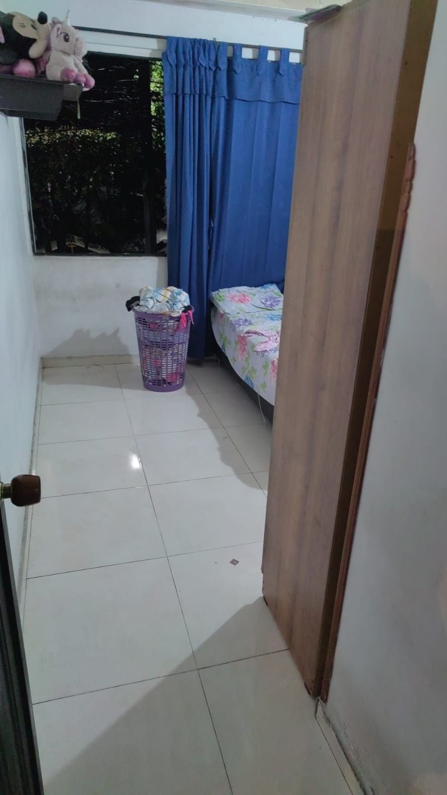 Un dormitorio con una cama y un cesto de ropa dentro.