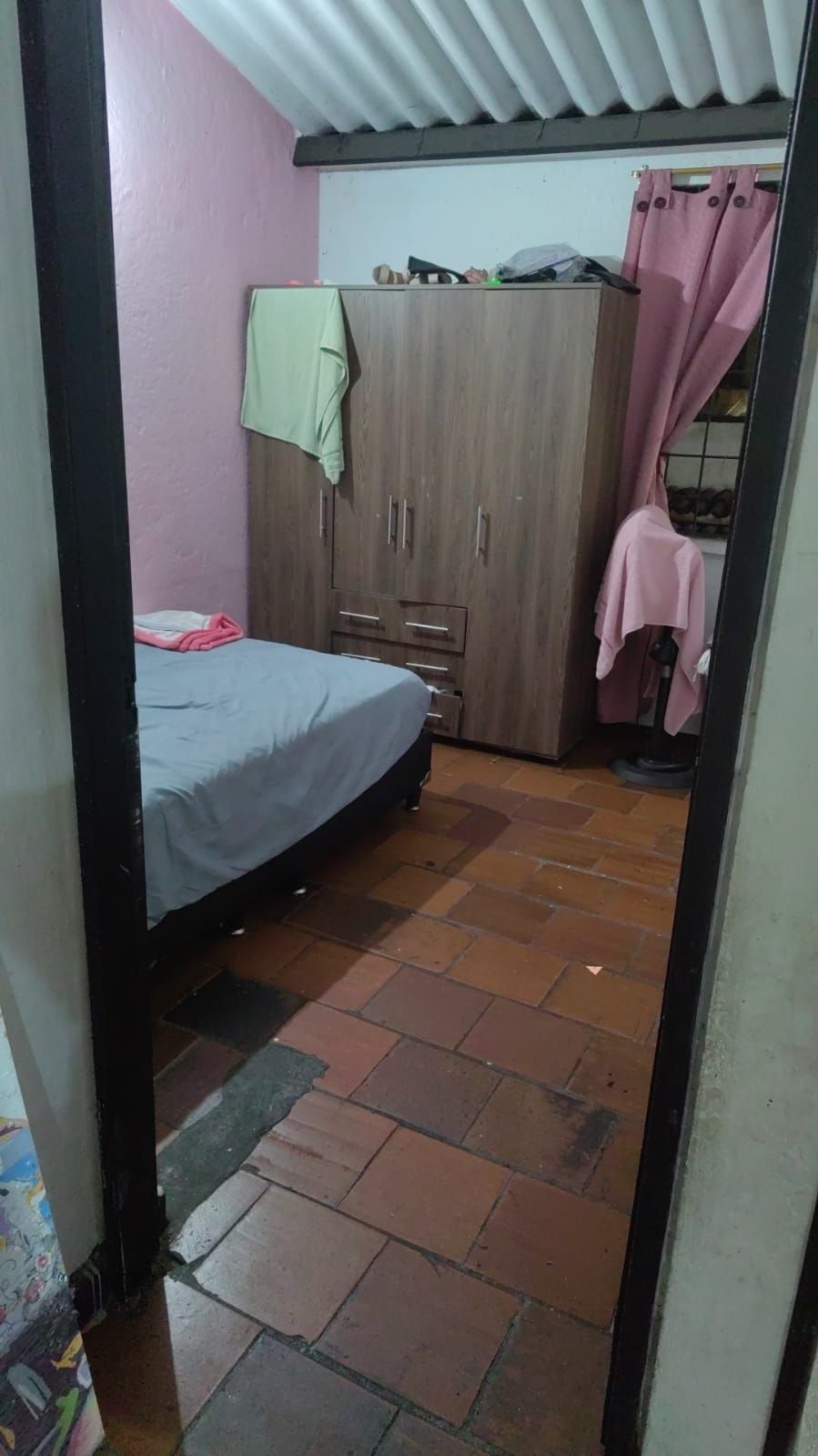 Un dormitorio con cama, armario y suelo de baldosas.