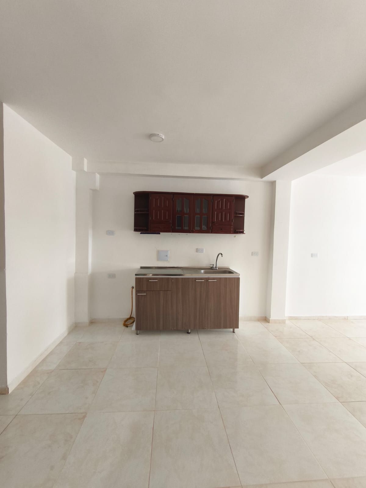 Una cocina con fregadero y armarios en una habitación vacía.