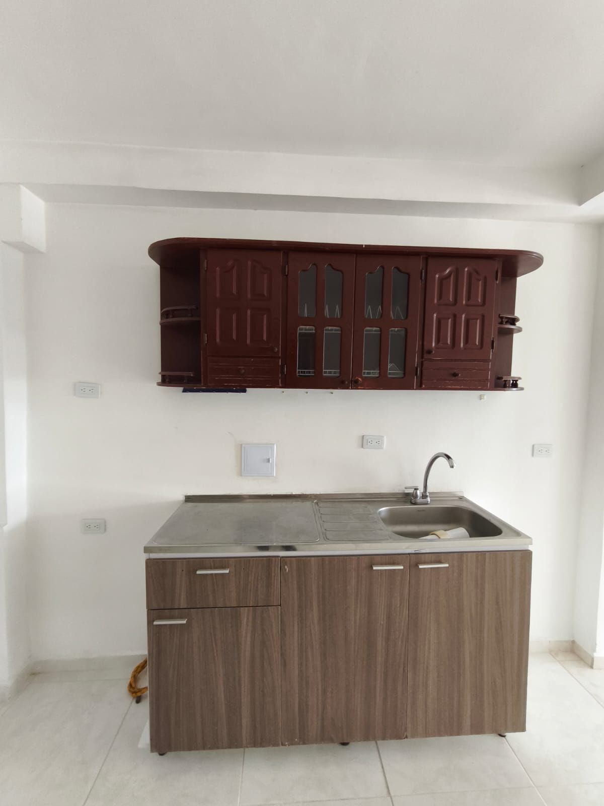Una cocina vacía con gabinetes de madera y un fregadero.