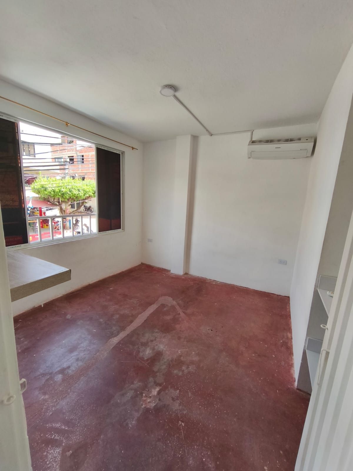 Una habitación vacía con un suelo rojo y una ventana.