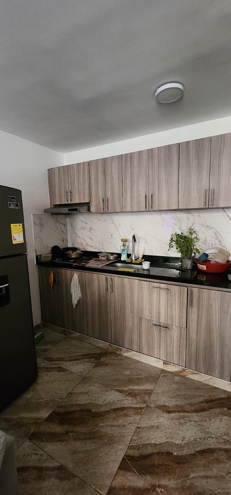 Una cocina con refrigerador, fregadero y armarios.