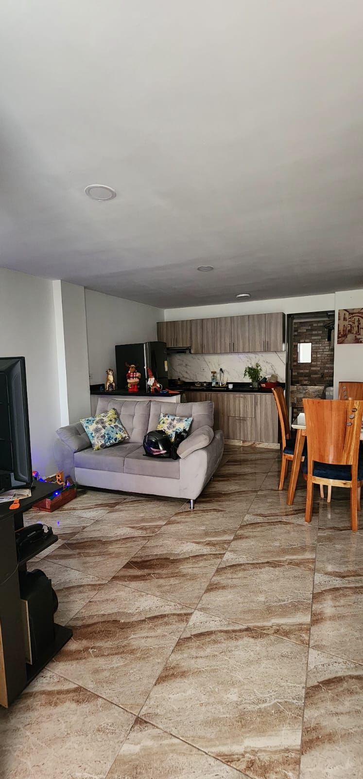 Una sala de estar con sofá, televisión, mesa de comedor y sillas.
