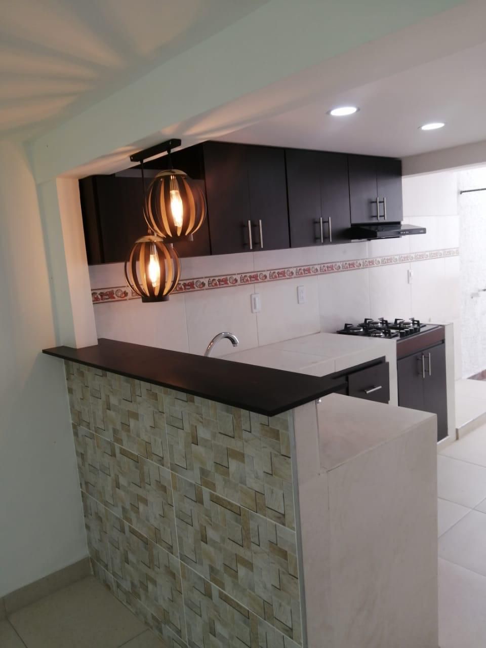 Una cocina con una pared de ladrillo y dos lámparas colgando del techo.