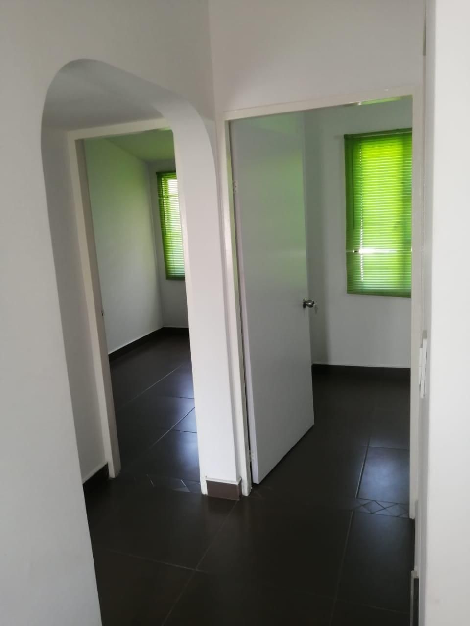 Una habitación vacía con una puerta y dos ventanas.