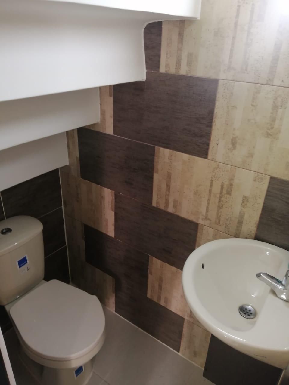 Un baño con inodoro y lavabo debajo de las escaleras.