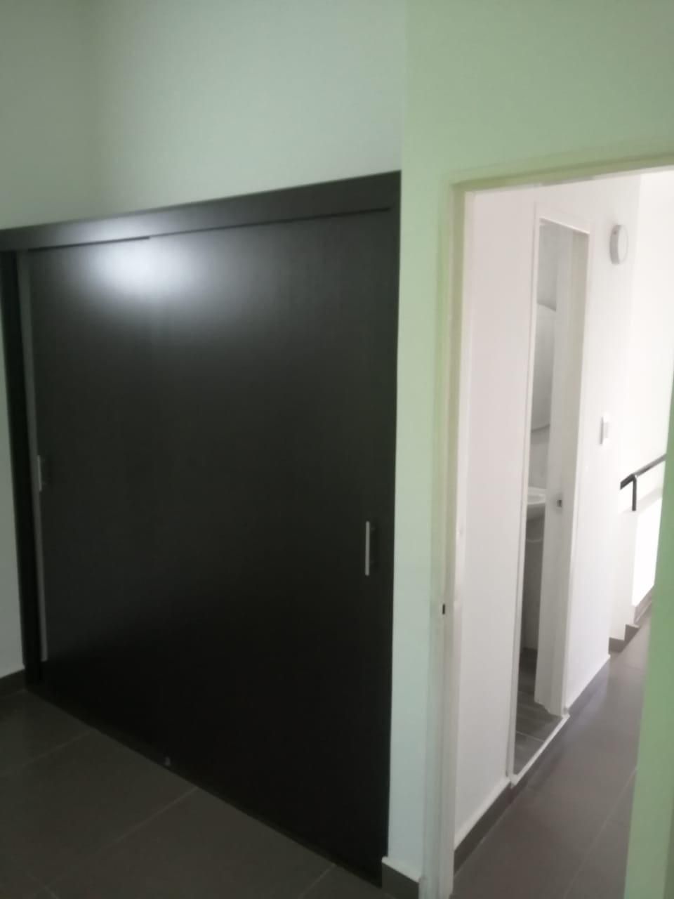 Un pasillo con una puerta corrediza negra que conduce a un baño.