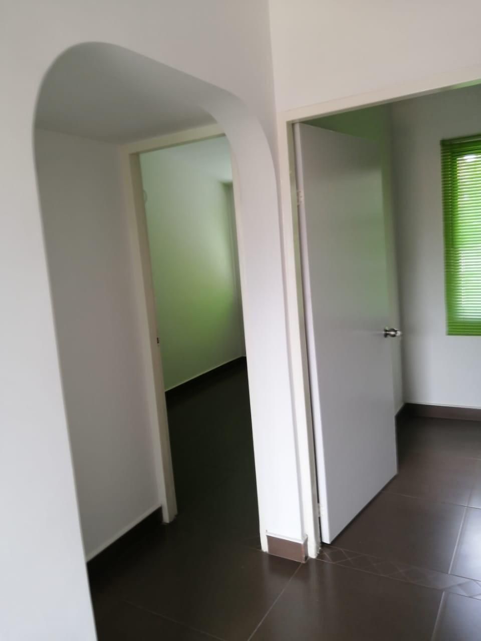 Una habitación vacía con una ventana verde y una puerta blanca.