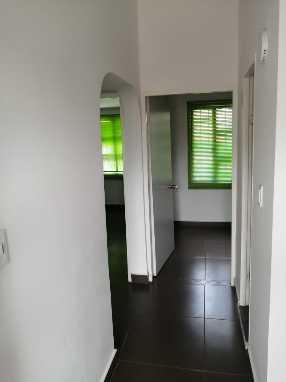 Un pasillo que conduce a una habitación con persianas verdes.