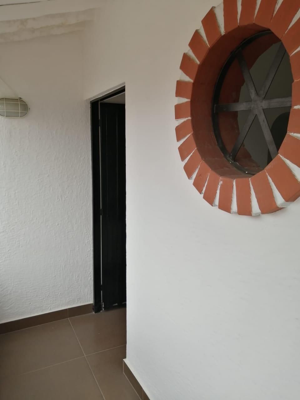 Una pared blanca con una ventana redonda.