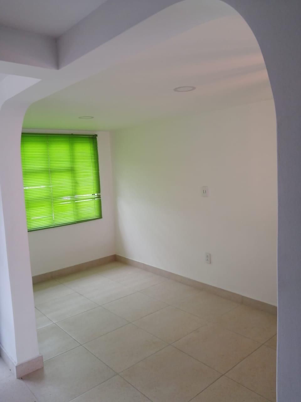 Una habitación vacía con una ventana verde y paredes blancas.