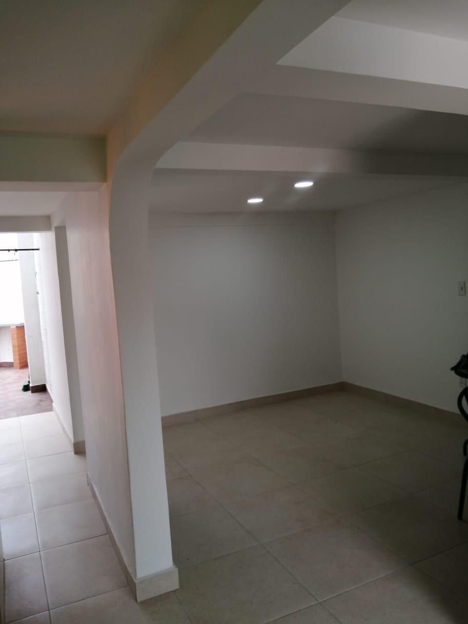 Una gran habitación vacía con paredes blancas y suelos de baldosas.