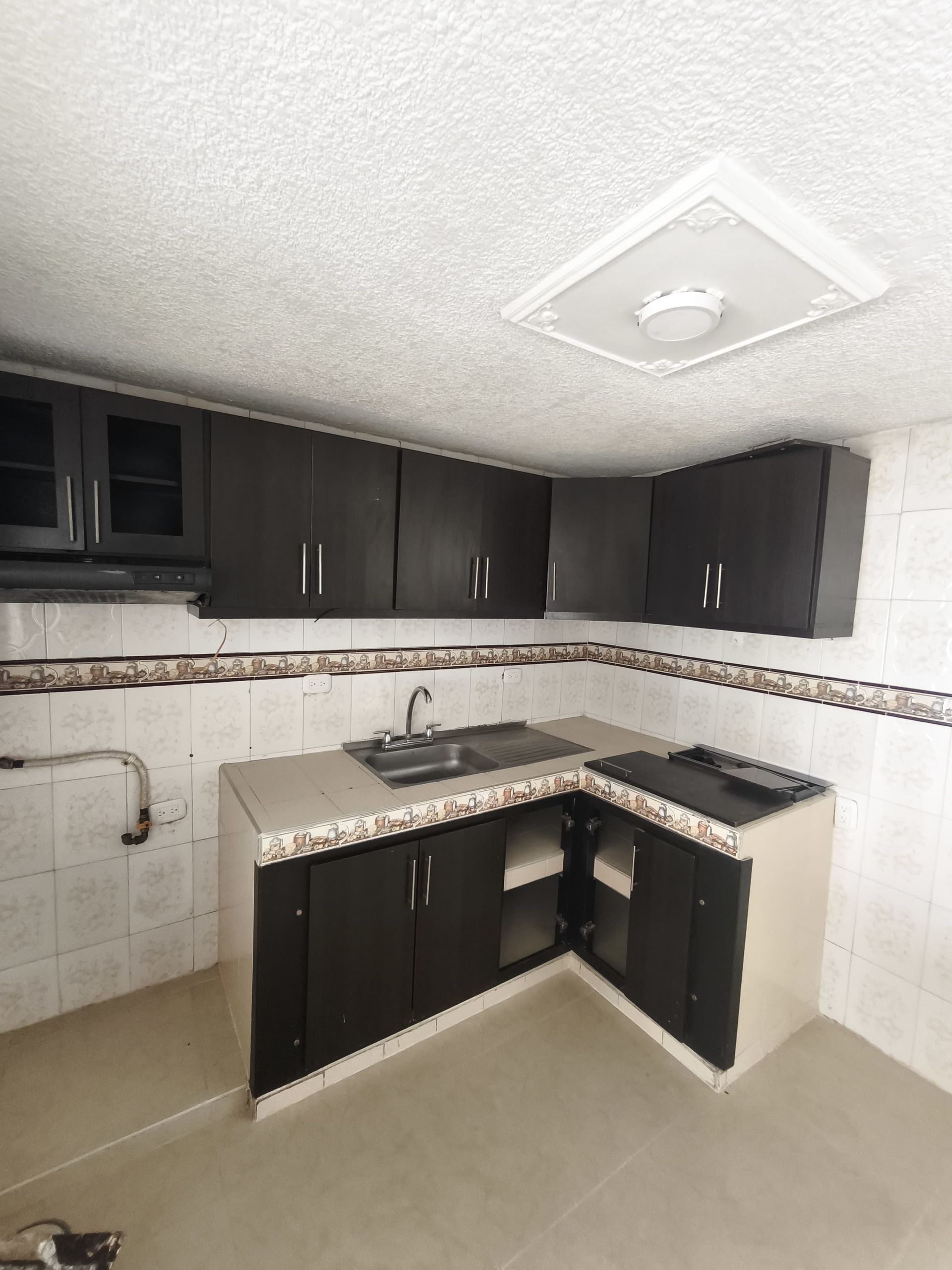 Una cocina con gabinetes negros y un fregadero.