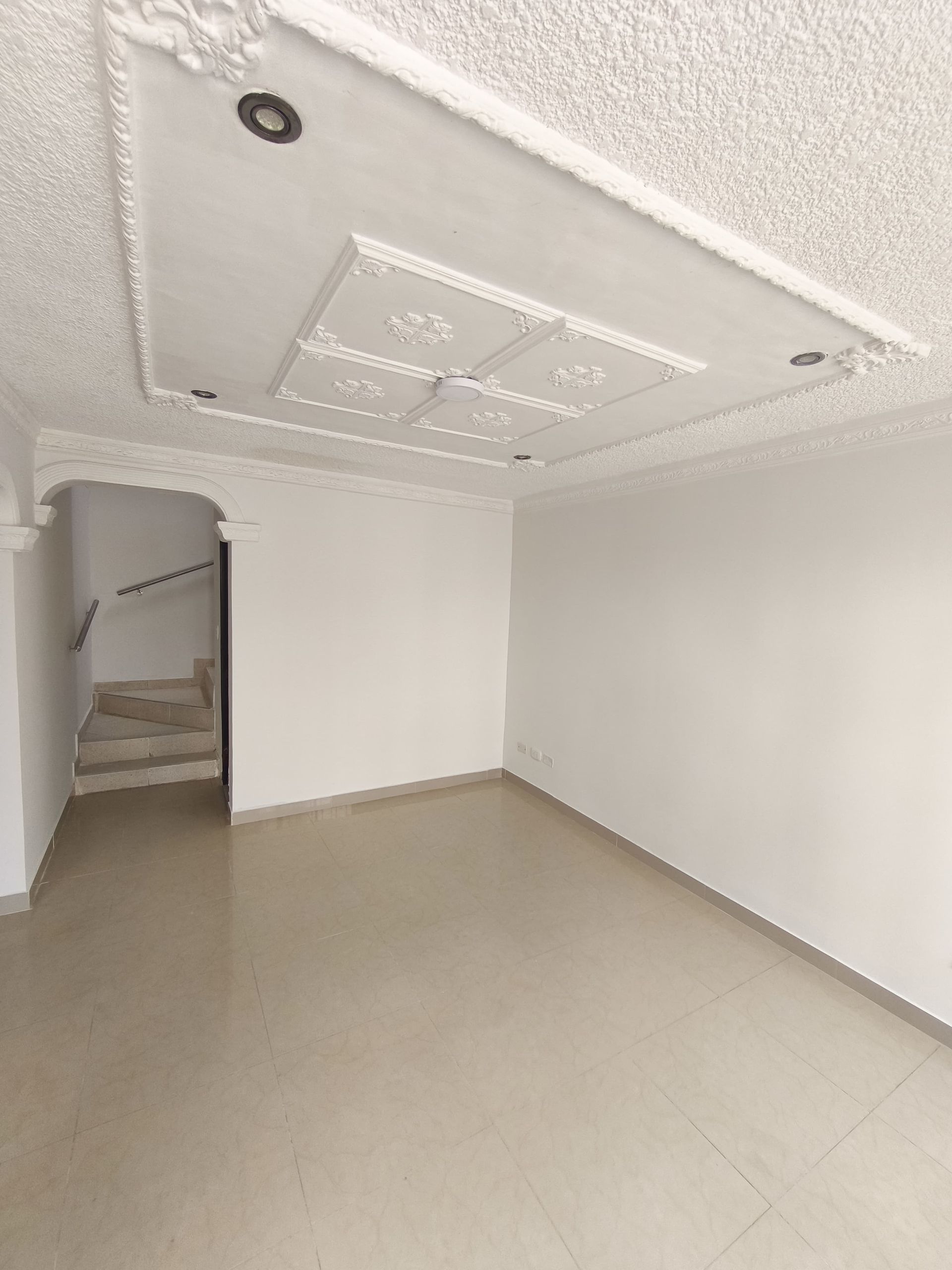 Una sala de estar vacía con escaleras que conducen al segundo piso.