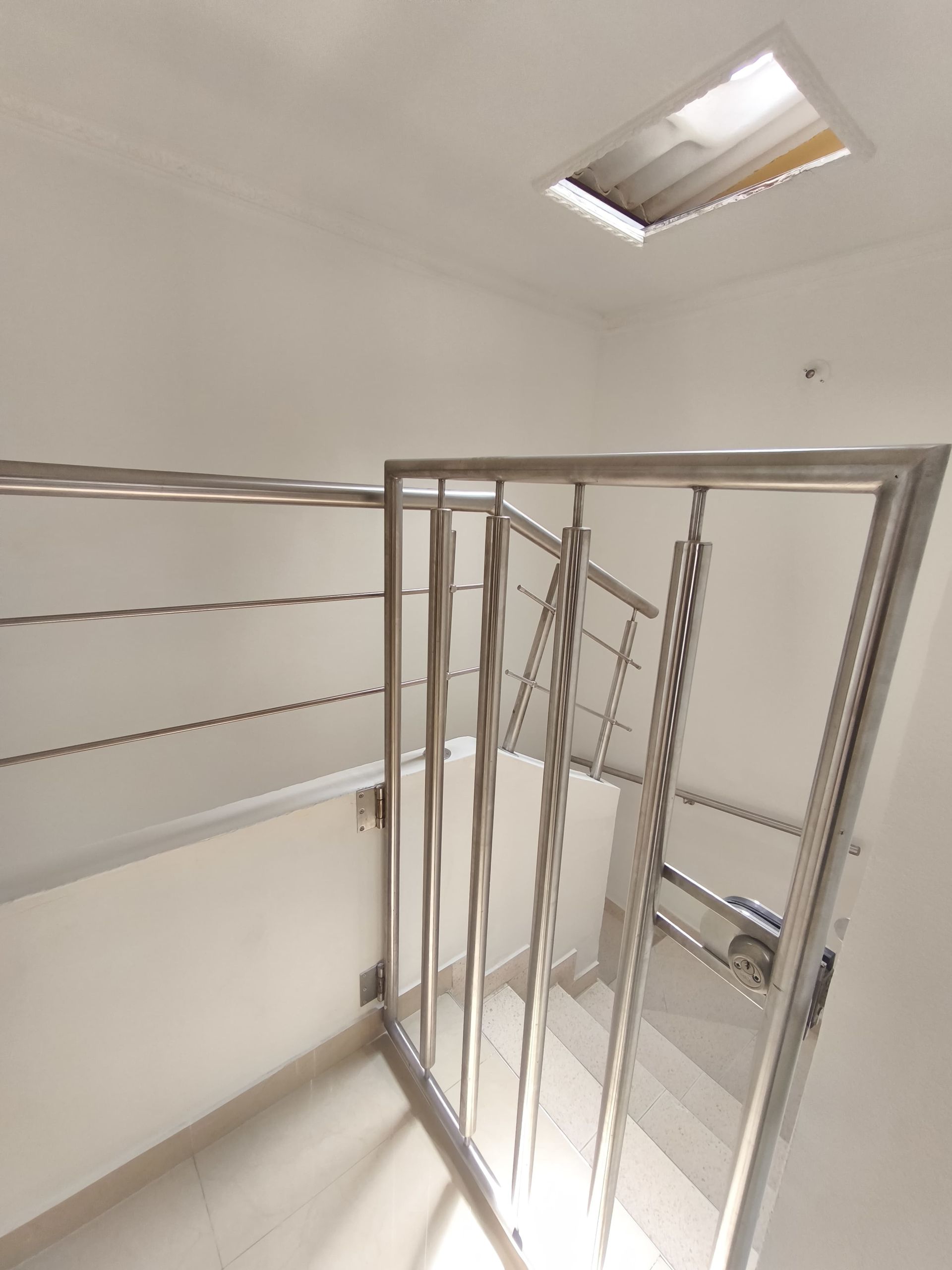 Una escalera con barandilla de acero inoxidable y luz de techo.