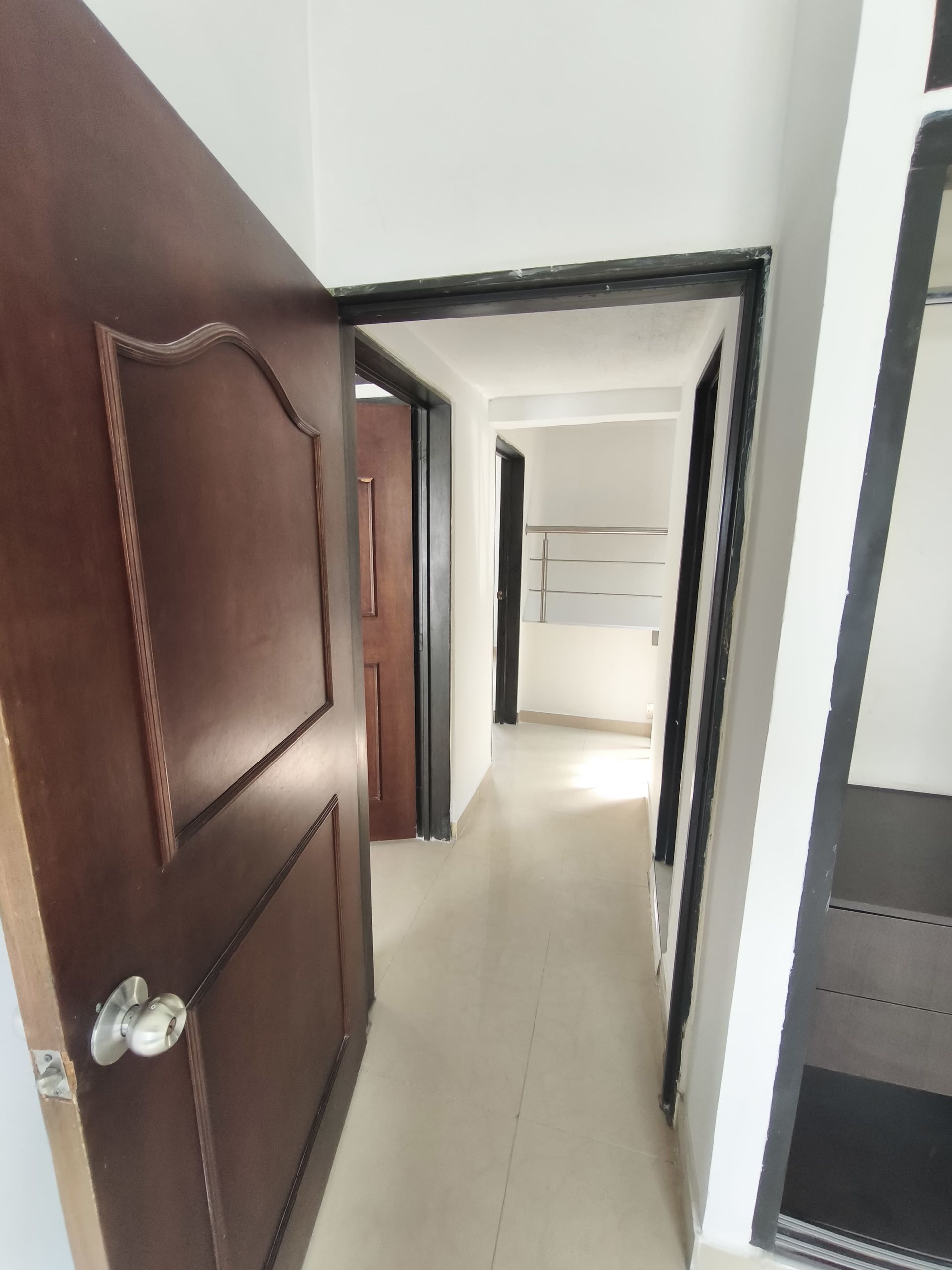 Un pasillo con una puerta de madera y una pared blanca.