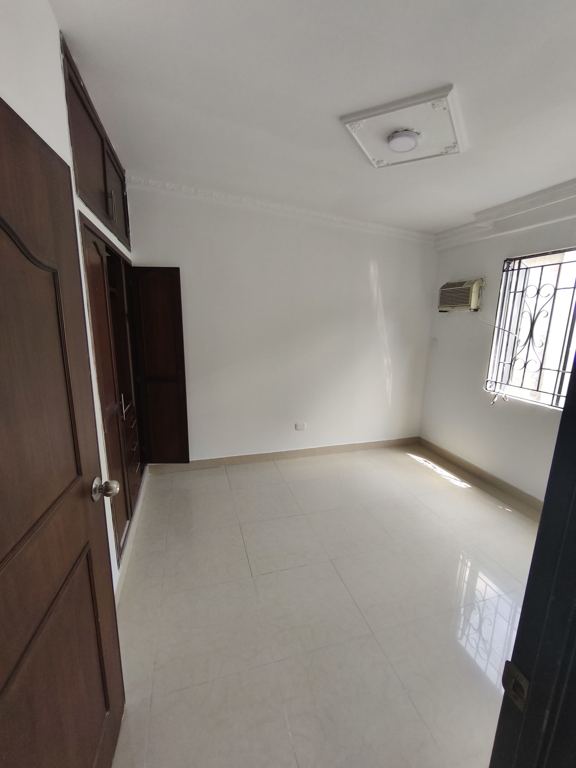 Una habitación vacía con una ventana y un ventilador en el techo.
