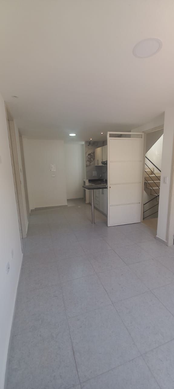 Una gran habitación vacía con cocina y escaleras.