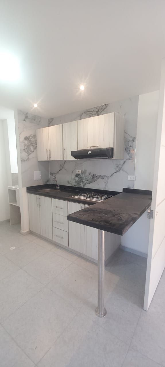 Una cocina con gabinetes blancos y una encimera negra.