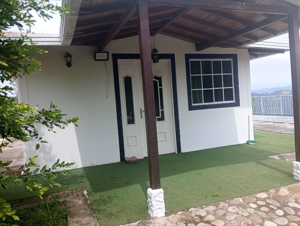 Una pequeña casa blanca con un porche de madera y una ventana.