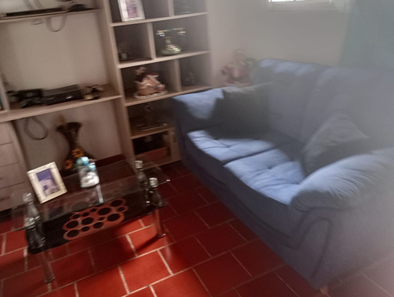 Una sala de estar con un sofá azul y una mesa de centro de cristal.