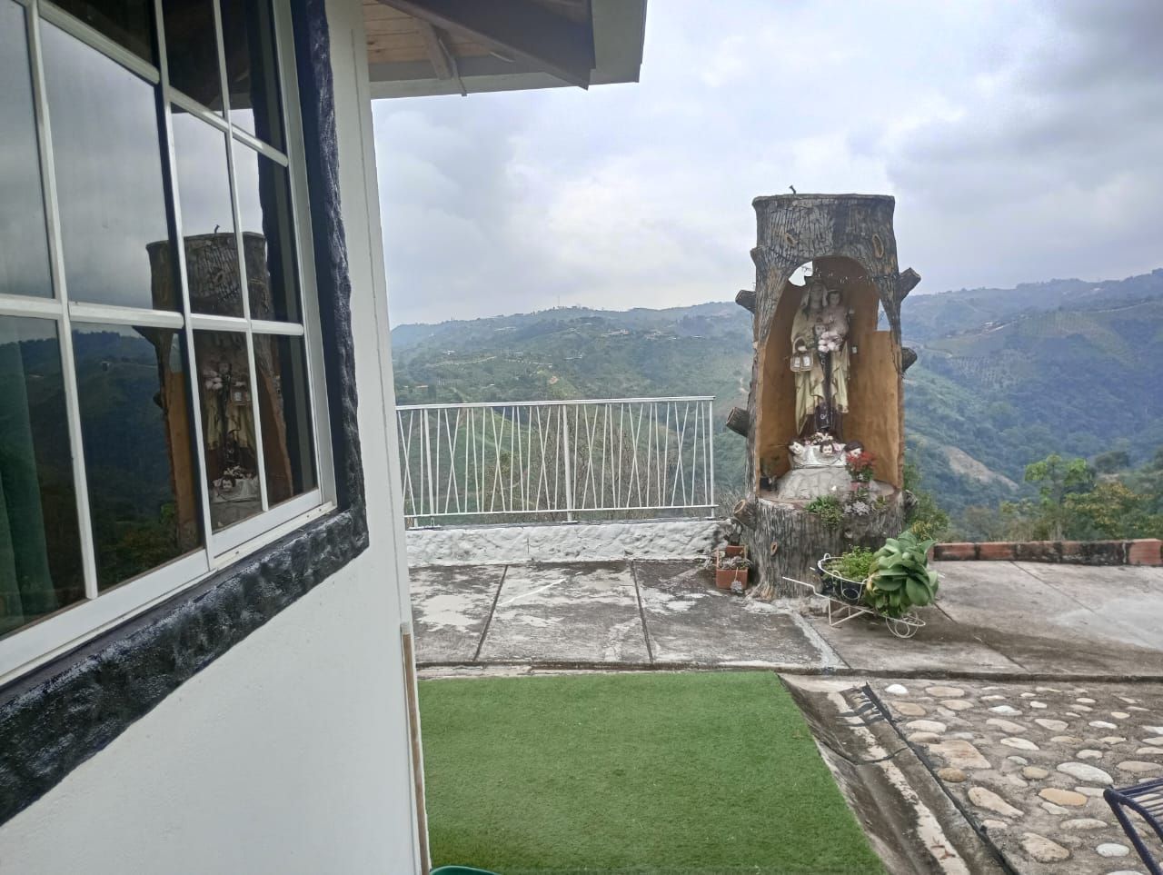 Una estatua de Jesús está sentada frente a una ventana con montañas al fondo.