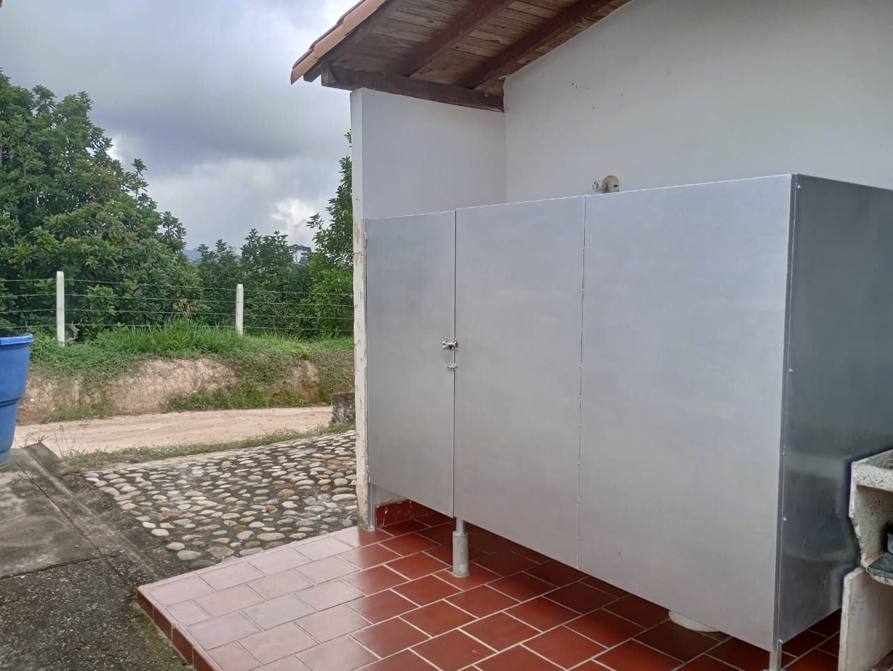 Un baño con ducha y lavabo fuera de un edificio.