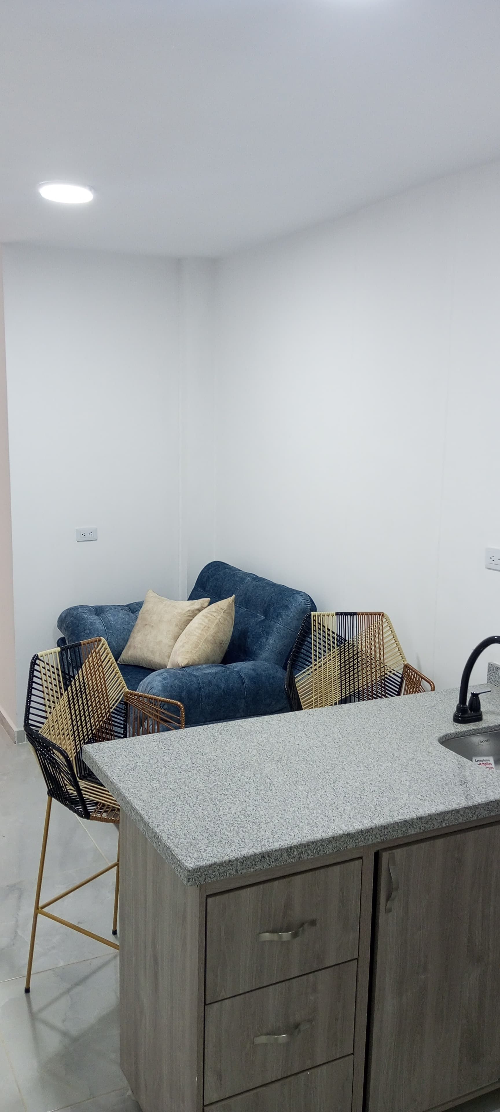 Una sala de estar con un sofá y una cocina con fregadero.