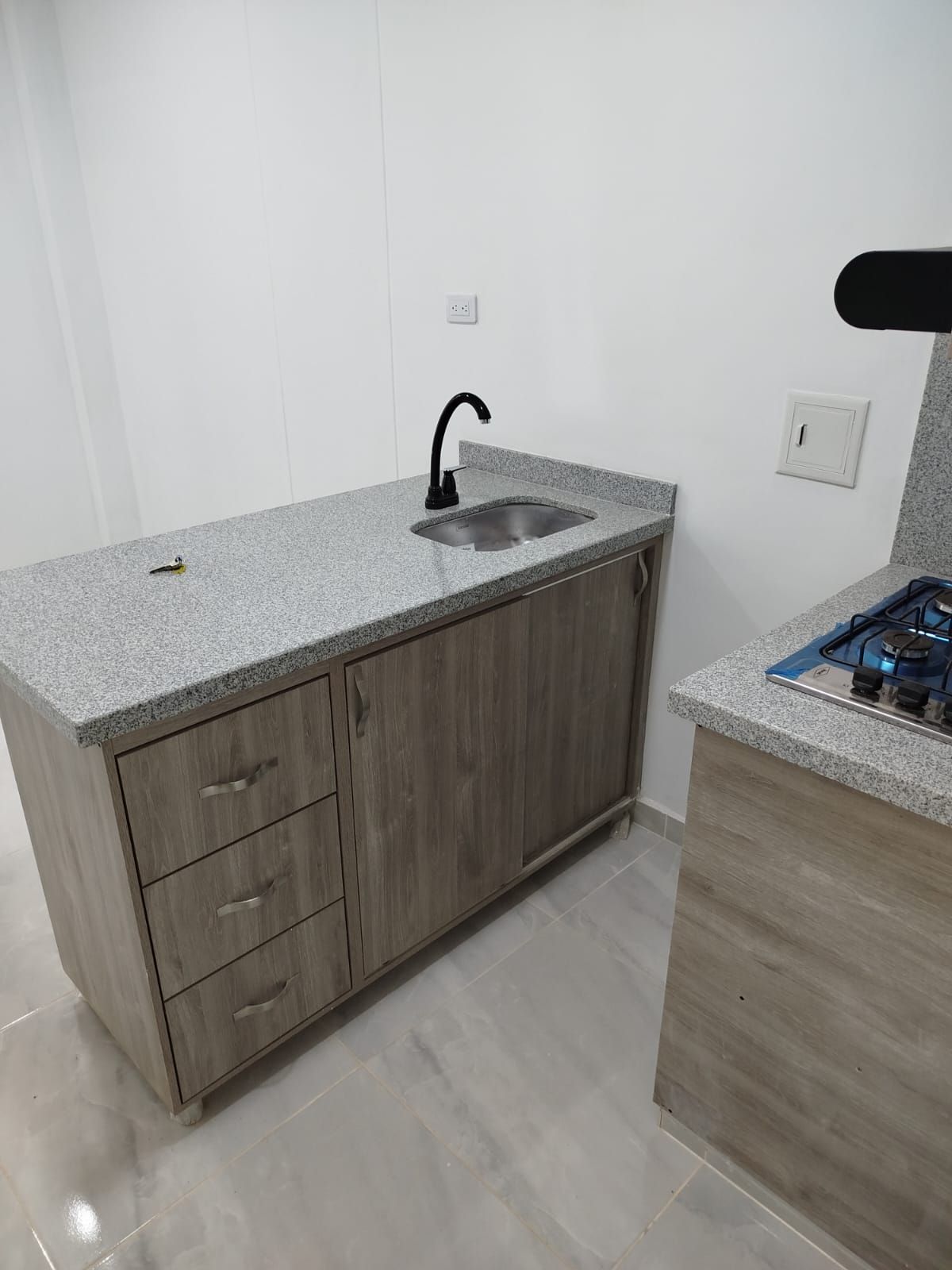 Una cocina con fregadero, estufa y campana extractora.