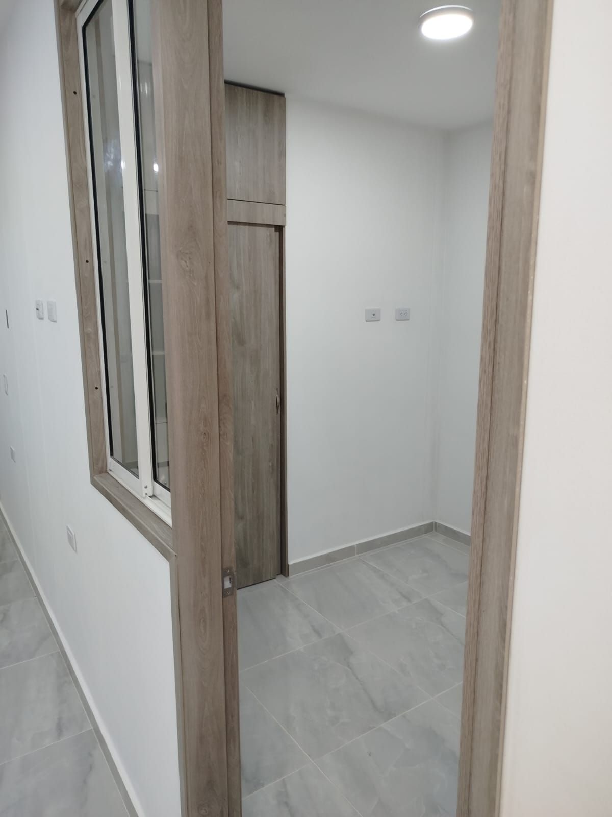 Un pasillo con una ventana y una puerta en una casa.