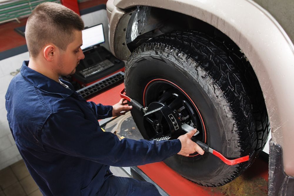 A Man Is Adjusting A Tire On A Car In A Garage — Nuron Inspection & Service Centre In Broadmeadow, NSW