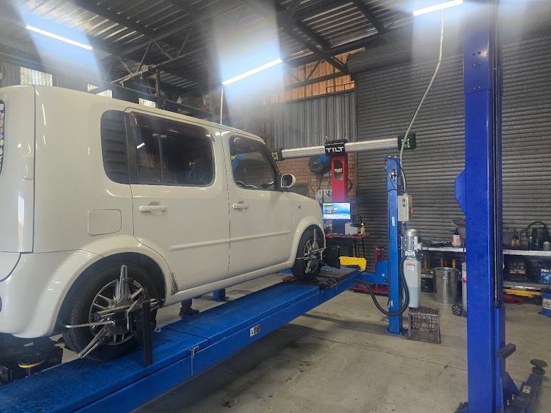 A White Van Is Sitting On Top Of A Blue Lift In A Garage — Nuron Inspection & Service Centre In Broadmeadow, NSW
