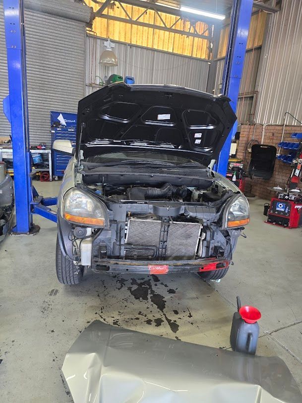A Car With The Hood Up Is Sitting On A Lift In A Garage — Nuron Inspection & Service Centre In Broadmeadow, NSW