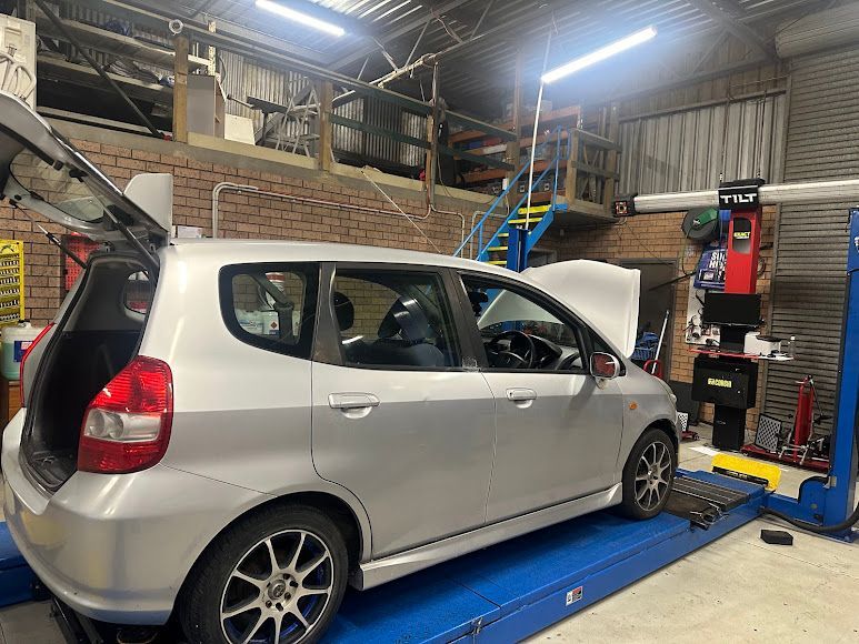 A Silver Car Is Sitting On A Lift In A Garage — Nuron Inspection & Service Centre In Broadmeadow, NSW