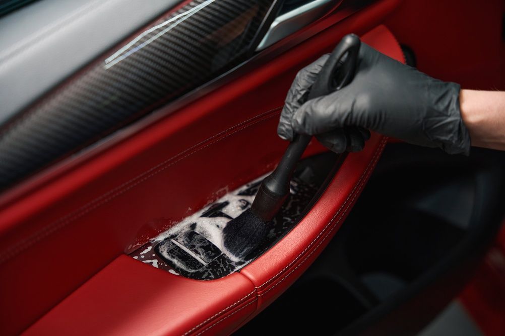Gloved hand applying polish to a red car door panel with a carbon fiber accent — Nuron Inspection & Service Centre In Broadmeadow, NSW