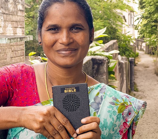 Tataya holding his Talking Bible on the plains of Tanzania