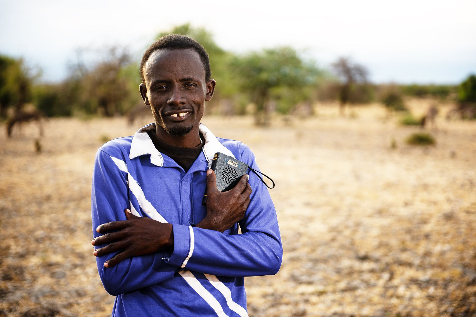 Tataya holding his Talking Bible on plains of Tanzania.