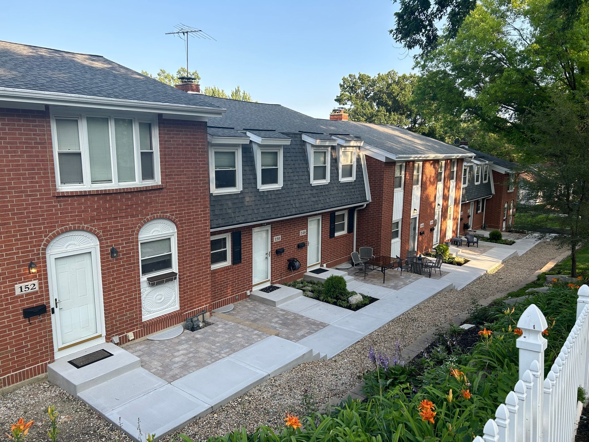 a row of brick houses with a white fence in front of them .