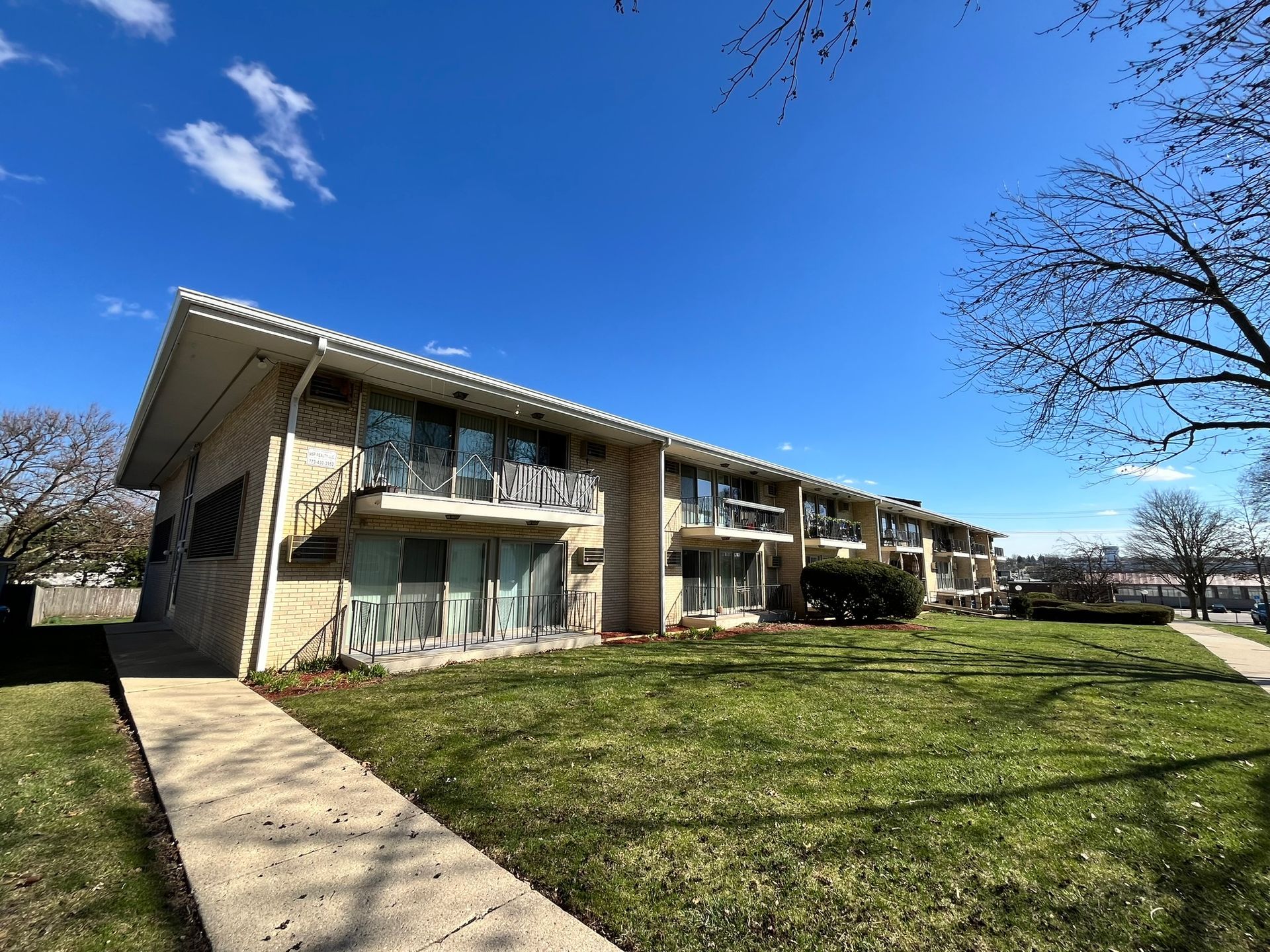 a large apartment building with a lush green lawn in front of it .