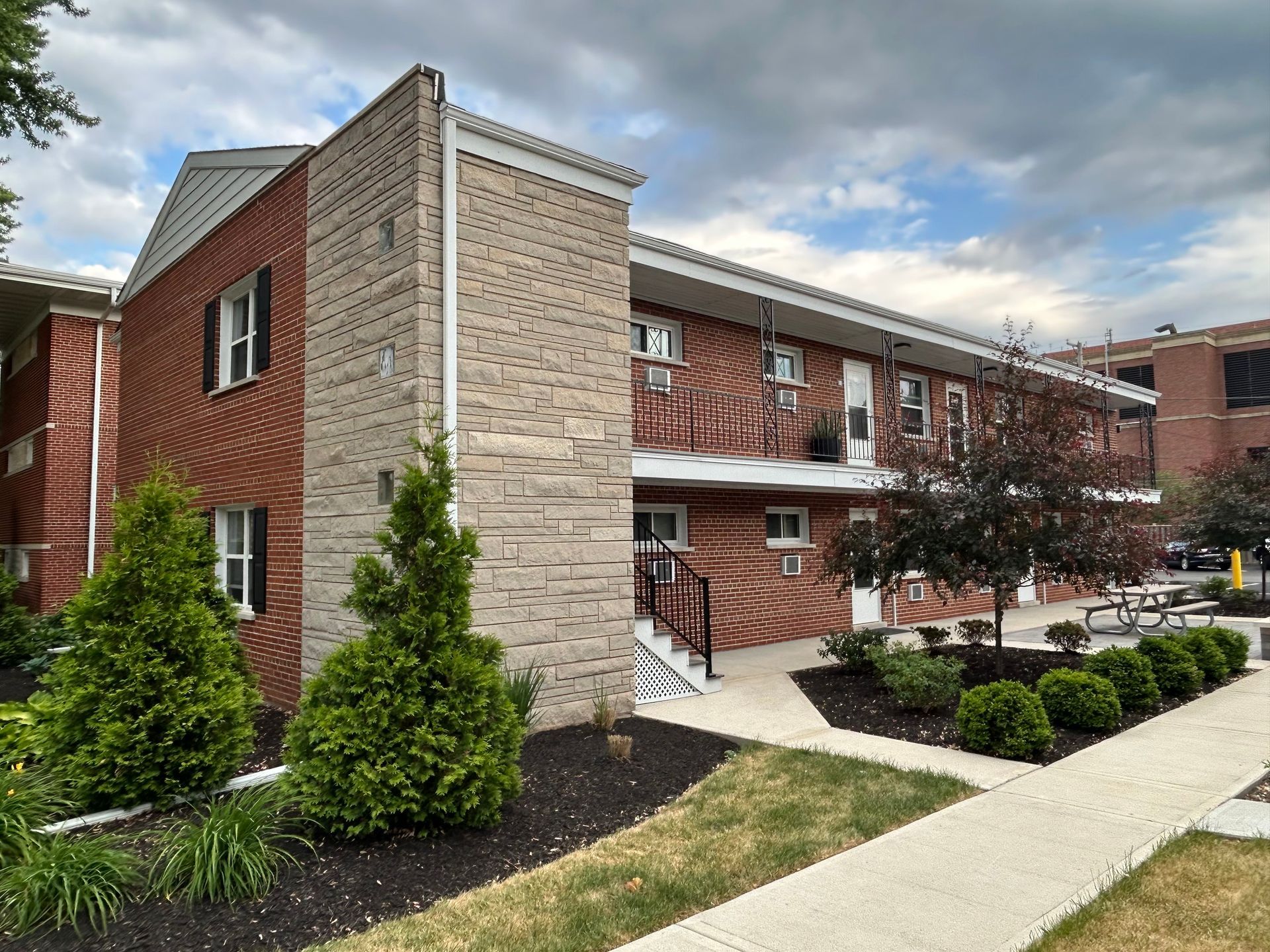 a brick apartment building with a sidewalk in front of it