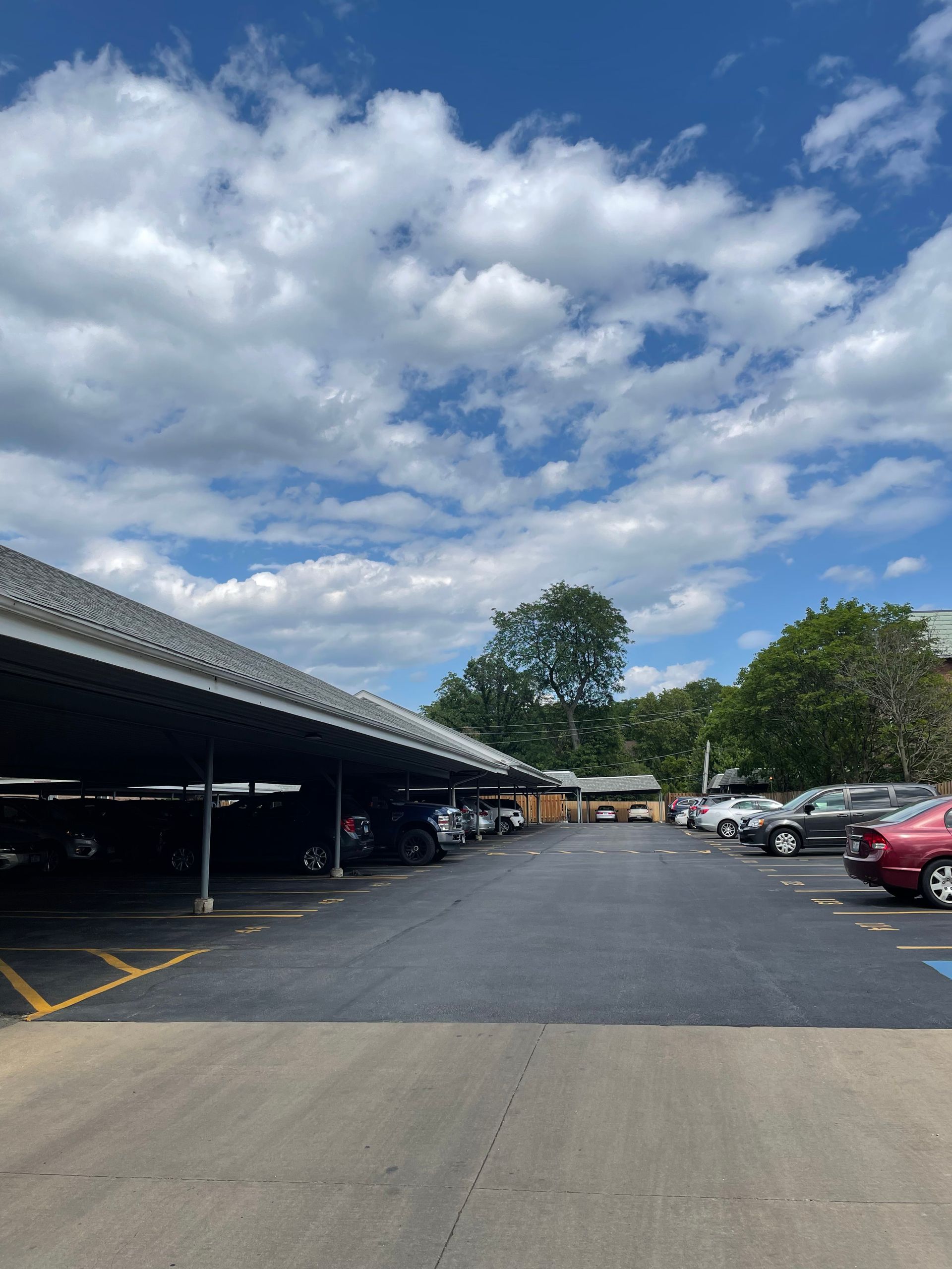 a parking lot with cars parked under a canopy on a sunny day .