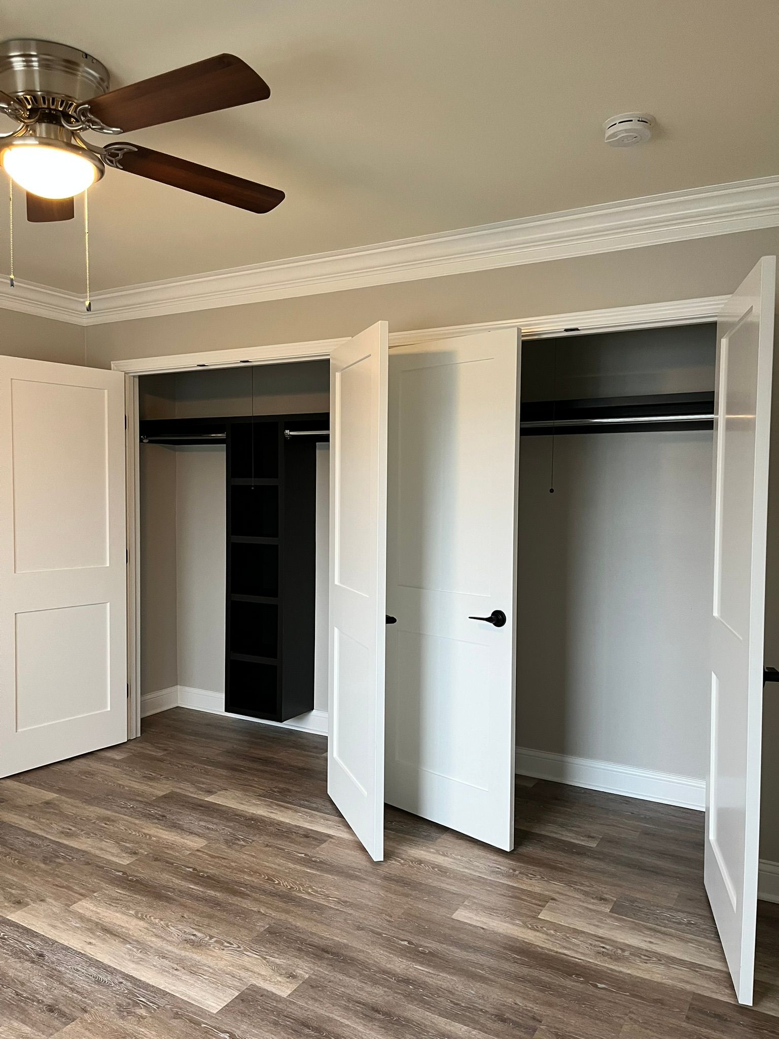 A bedroom with a ceiling fan and a lot of closets.
